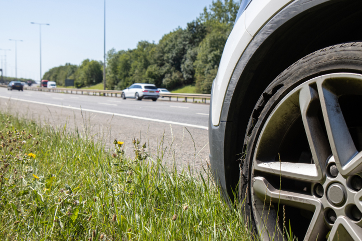 Car with flat tyre by hard shoulder